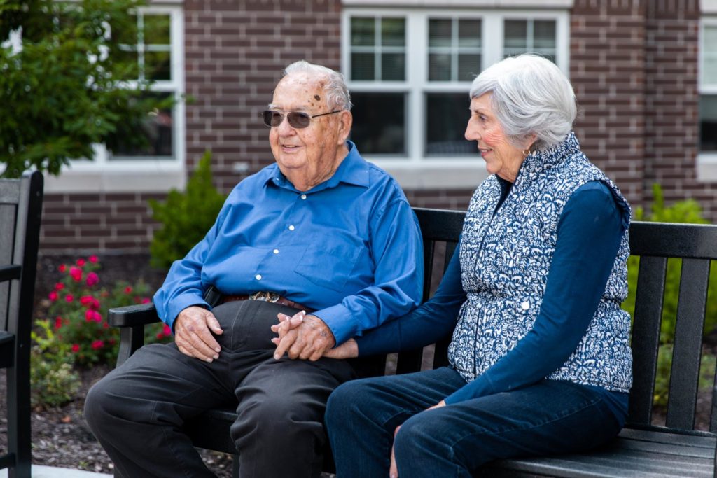 portrait of mature couple on a park bench for aging loved ones discussion in kansas city