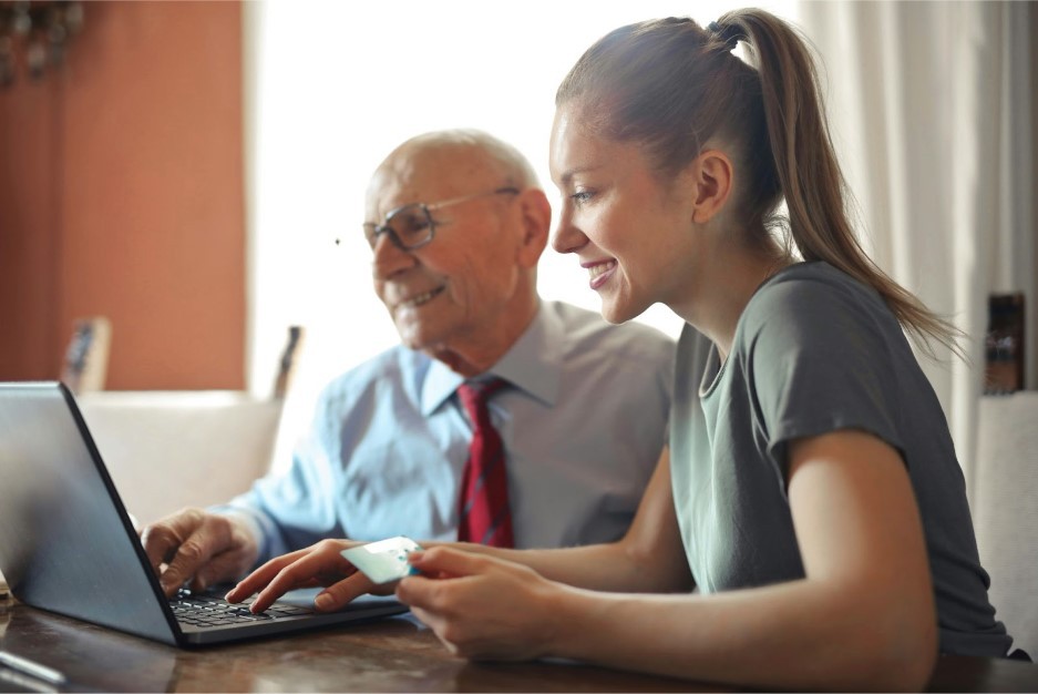 family member helping elderly man place an online order with his credit card