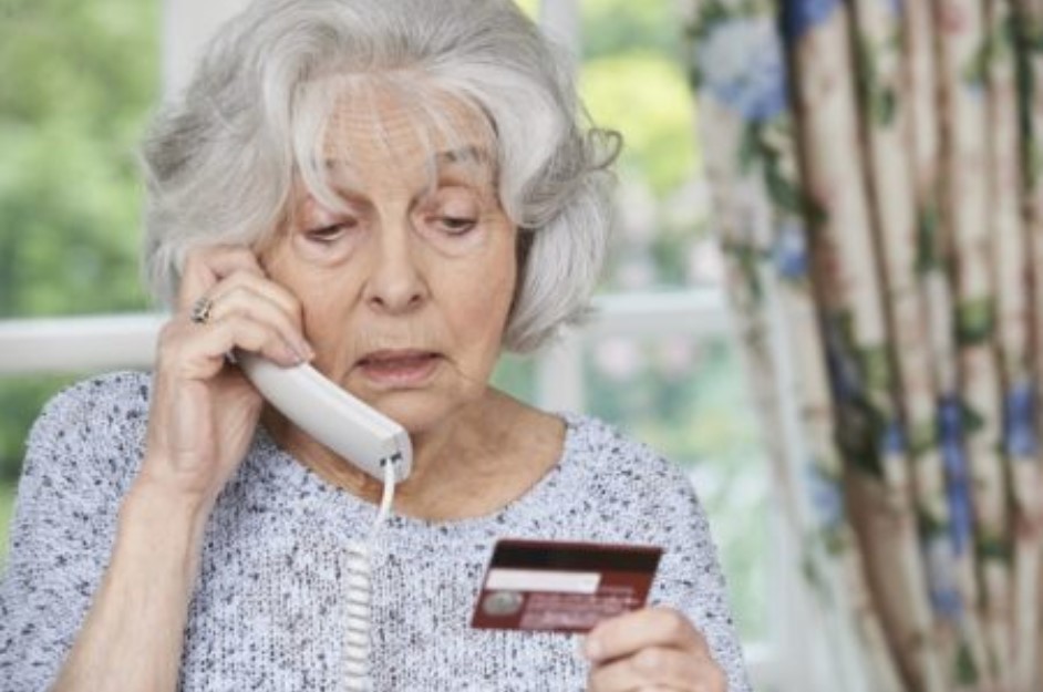 Senior woman on the phone reading her credit card number to someone